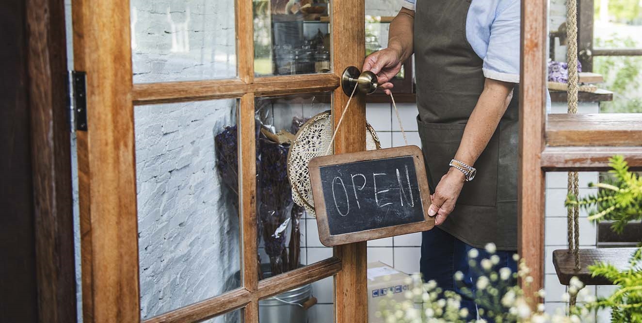 person hanging an open sign on a door